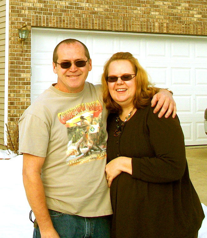Mike and Kim Smiling in front of their home
